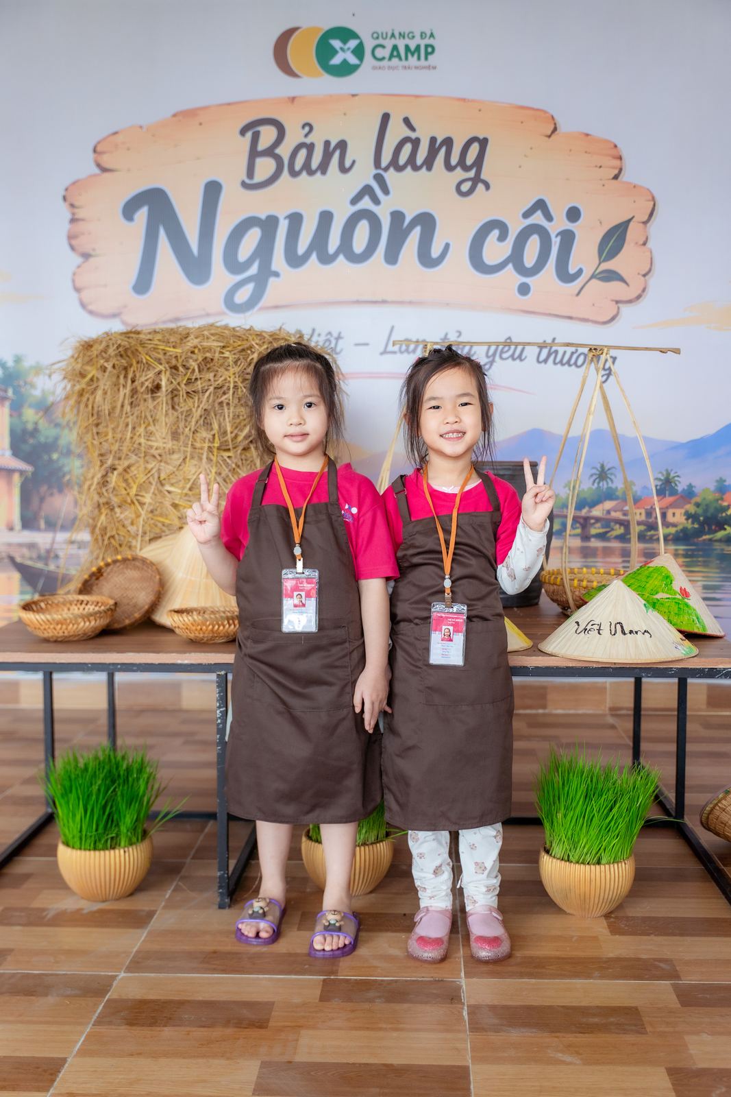 Hai bạn nhỏ trước phông Bản Làng Nguồn Cội